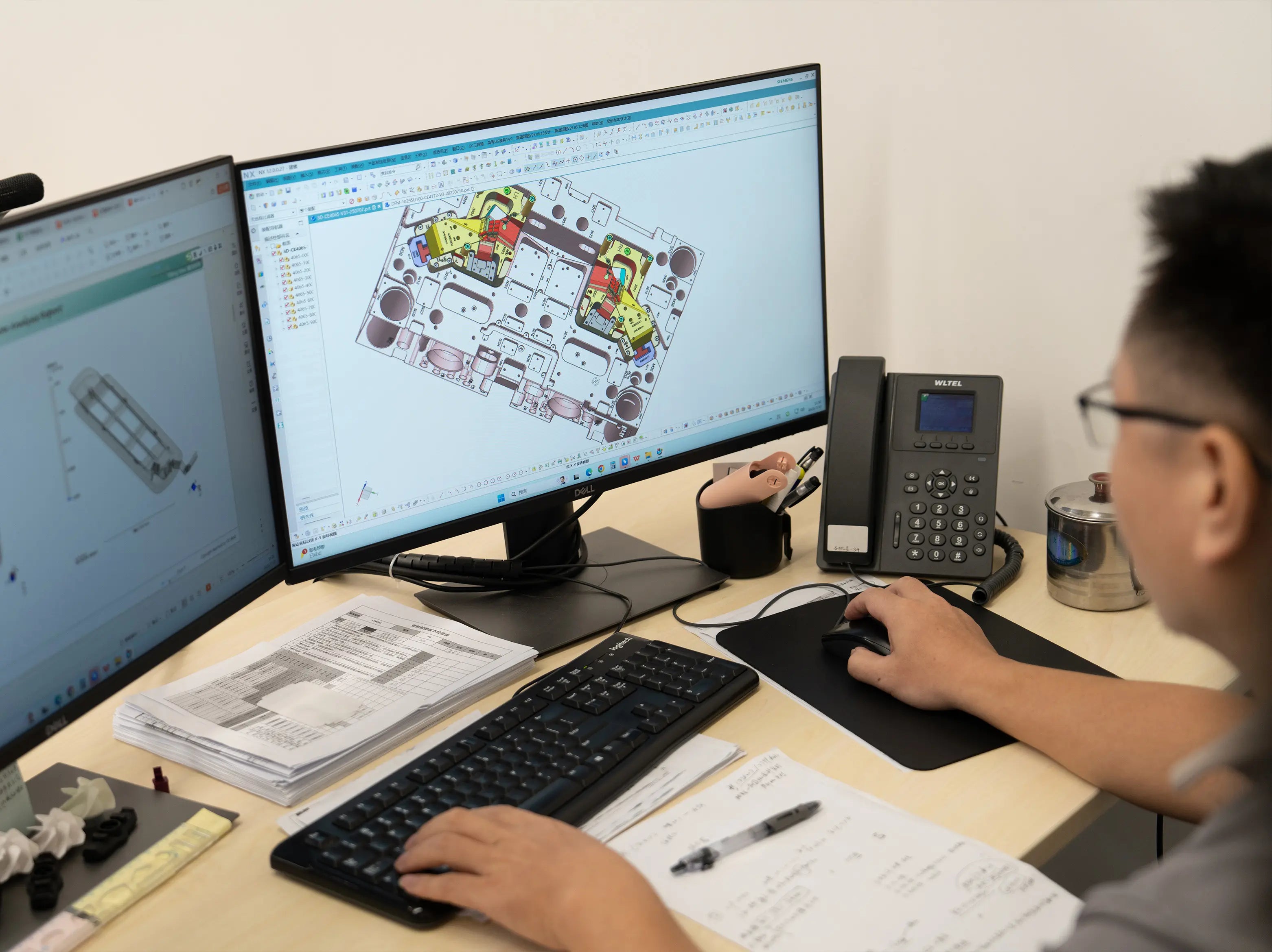 Engineer reviewing a plastic injection mold design on dual CAD workstations