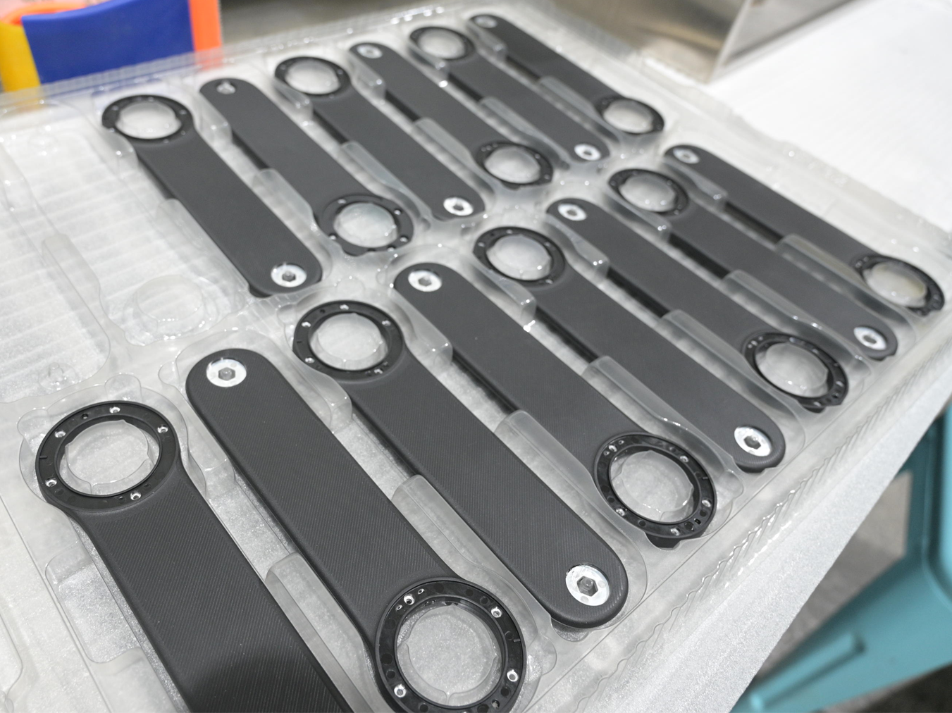 Black molded plastic components arranged in protective trays after production.