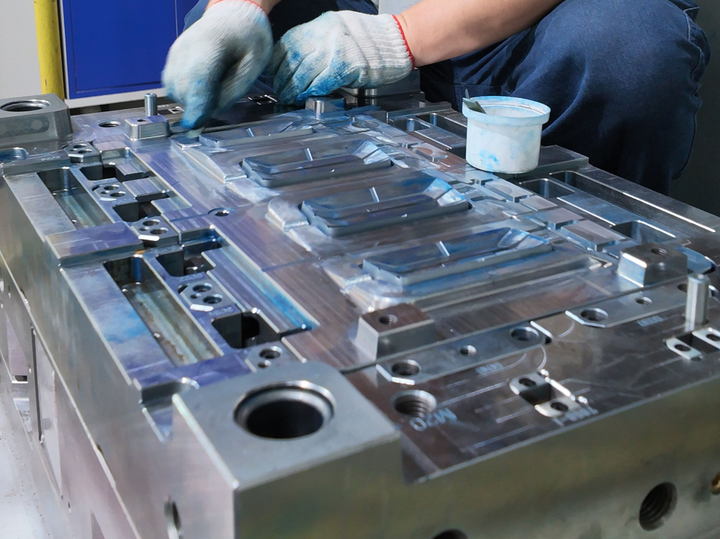 Technician applying blue compound to precision mold during mold design and manufacturing inspection