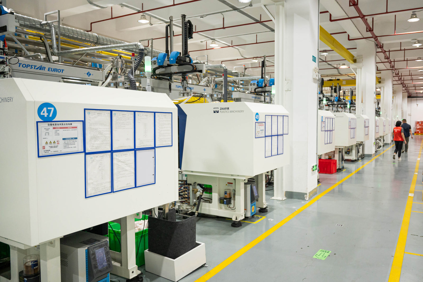Modern injection molding floor with clear safety markings and organized production lines.