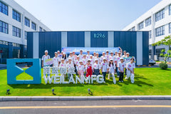 Group photo of all participating children and staff in front of the Weilan MFG factory sign and building