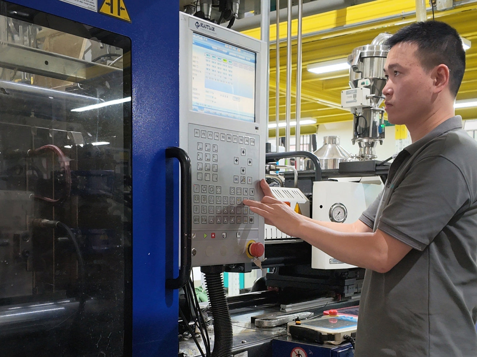 Operator adjusting the control panel of an injection molding machine