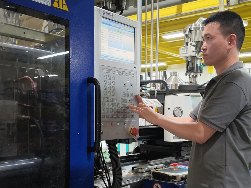 Operator adjusting the control panel of an injection molding machine