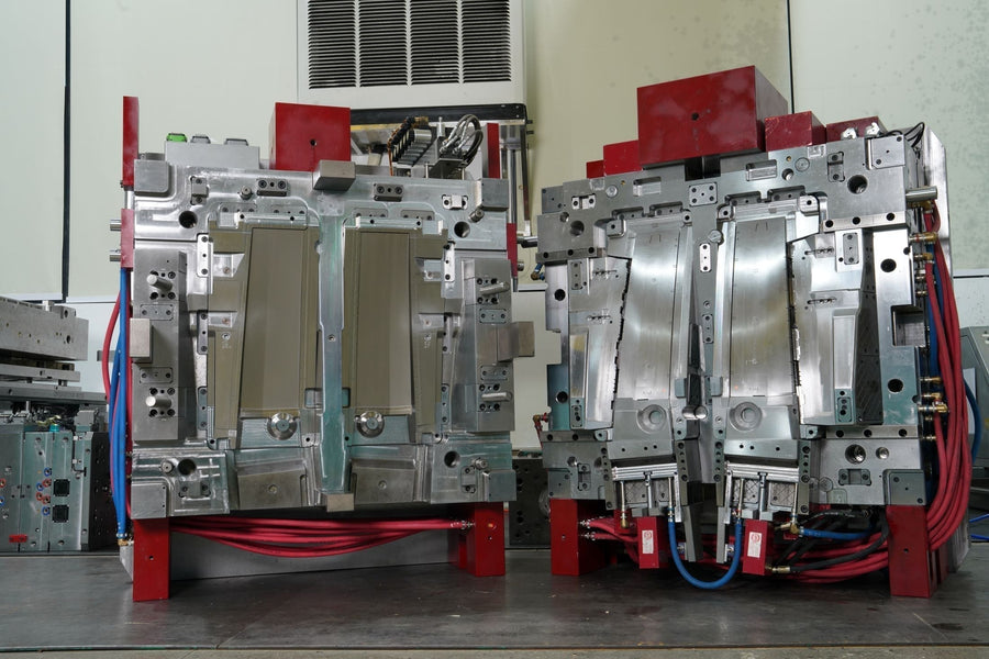 Two large, durable steel plastic injection mold halves standing upright on a factory floor, showcasing the complex internal cavity design for high-volume manufacturing.