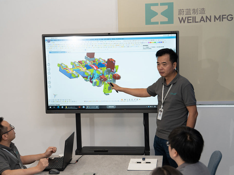 Engineer presents CAD mold design on a large screen during a Weilan MFG manufacturing team meeting
