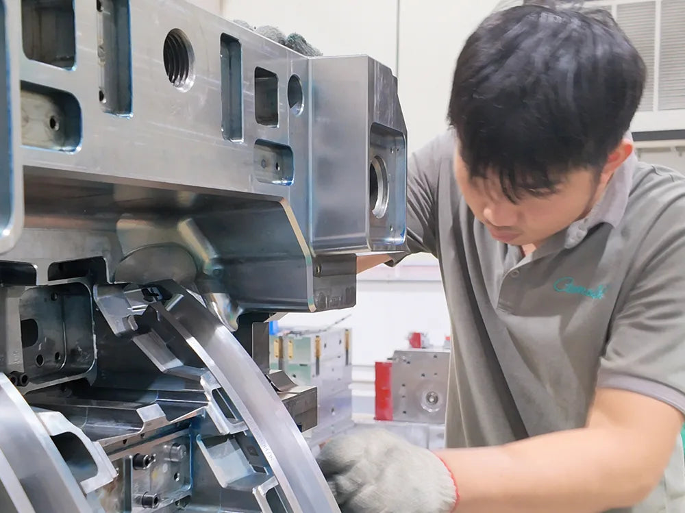 Technician inspecting and adjusting a metal injection mold in a manufacturing workshop