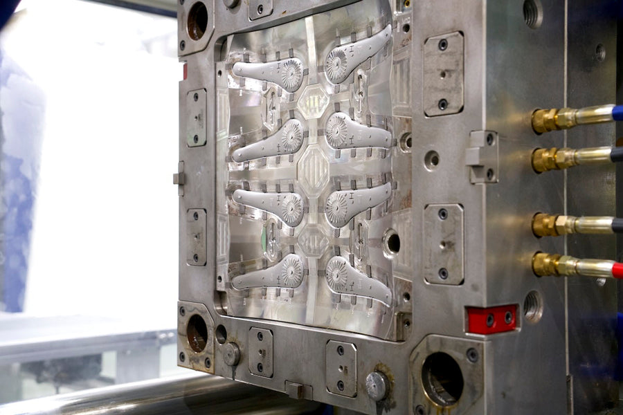 Close-up of a multi-cavity mold face with cooling connections, highlighting cavity layout and tooling details important for balanced production.