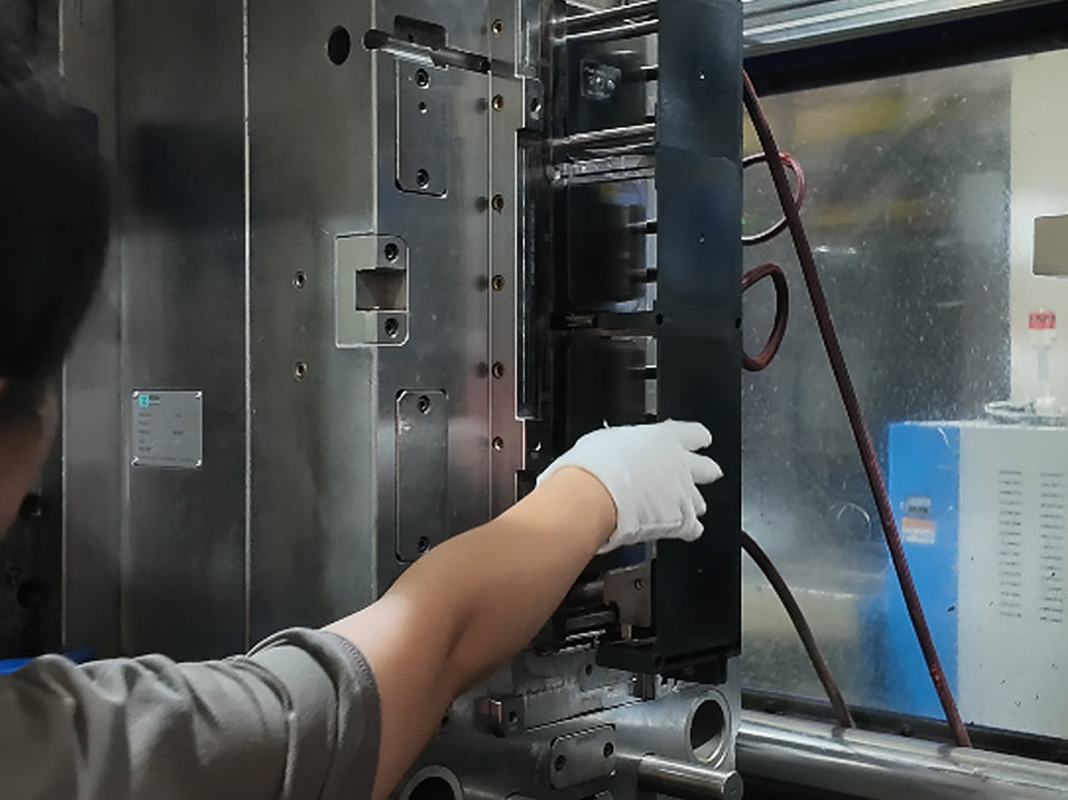 Operator inspecting a mold inside a plastic injection molding machine