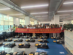 Full group photo of Weilan MFG employees with Red Cross instructors holding a red banner, with CPR manikins and AED units in the foreground