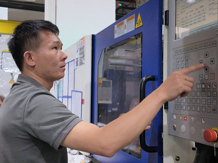 Technician operating an injection molding machine control panel